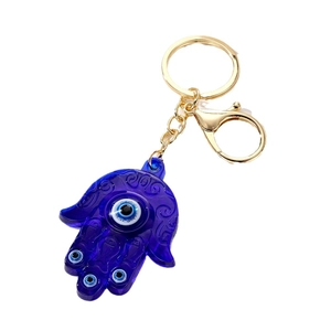 Porte-clés doré avec pendentif Main de Fatma bleue et motifs Œil du Diable sur fond blanc