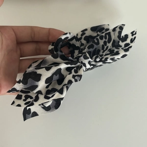 Detail of a black and white leopard print bow hair claw clip held in hand with macro view