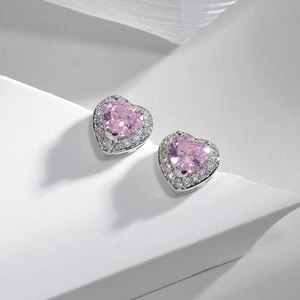Detailed view of heart-shaped pink ruby stud earrings with white zircon halo on white background