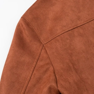 Detailed close-up of brown faux suede jacket shoulder stitching and matte fabric texture