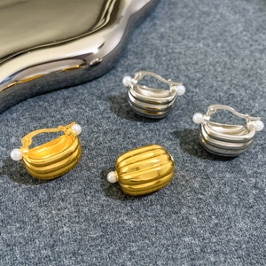 Detailed close-up of metallic threaded earrings featuring elegant white pearls on both ends