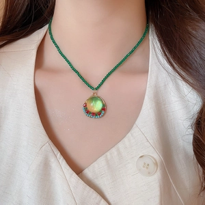 Detail of beaded green necklace with geometric resin pendant and colorful stones