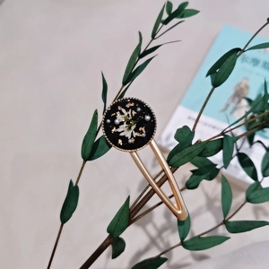 Close-up of handmade retro hair clip with dried flowers and gold foil in black resin