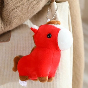 Macro shot of red plush pony charm with silver ball chain hanging on canvas bag