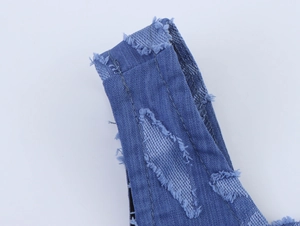 Gros plan détaillé des bretelles en jean usé avec bords effilochés et coutures apparentes