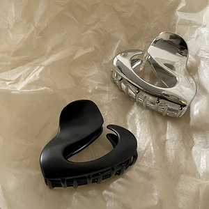 Detail view of heart-shaped hair claws in polished silver and matte black finishes