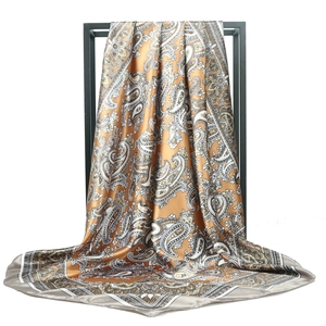 Golden brown paisley satin square scarf displayed on a minimalist black metal stand