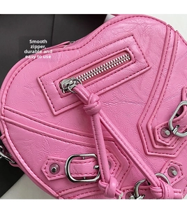 Détail du sac moto rose en forme de cœur avec texture cuir vintage et clous argentés