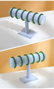 Detailed view of the gray suede T-bar jewelry stand displaying green beaded bracelets
