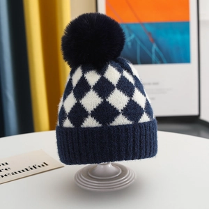 Close-up of navy blue knit winter hat with checkered pattern and soft fluffy pompom