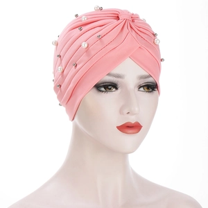 Detailed close-up of pink pleated turban hat featuring elegant pearl and metal bead accents