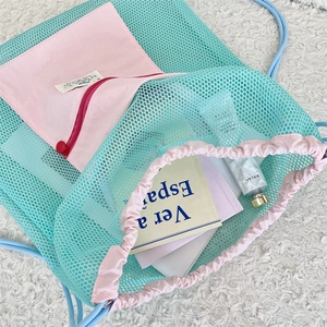 Detailed close-up of mint green mesh drawstring backpack with pink zipper pocket detail