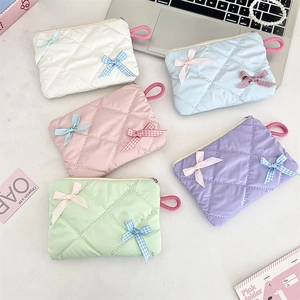 Flat lay of small bow makeup pouches in five colors with quilted pearl finish texture