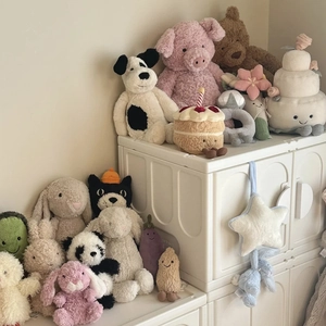 Collection of plush animal toys including rabbits and pandas on white storage bins