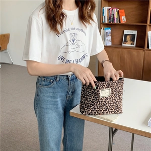 Close-up of leopard print canvas pouch held against denim and white t-shirt outfit