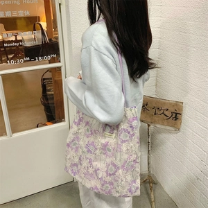 Detailed embroidery on purple floral lace tote bag worn by a model in casual setting