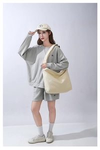 Inquadratura intera del modello con borsa tote in tela beige e abbigliamento grigio