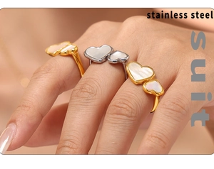 Close-up of gold and silver heart rings with mother of pearl inlay on finger