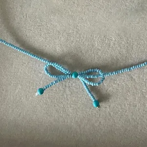 Gros plan d'un collier en perles bleu ciel fait main avec un nœud délicat