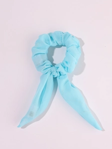 Detail of light blue LED scrunchie with bow tails made of soft fabric on white background