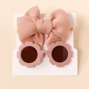 Dettaglio del set fascia con fiocco rosa e occhiali da sole a fiore per neonati