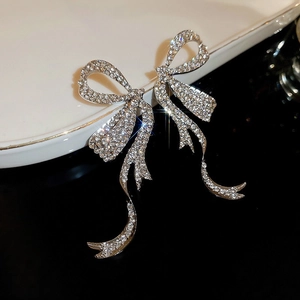 Macro shot of silver bow tassel earrings with micro-paved rhinestones and starry effect