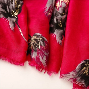 Detail of red cotton-linen scarf with black leaf print and gold foil accents and fringe