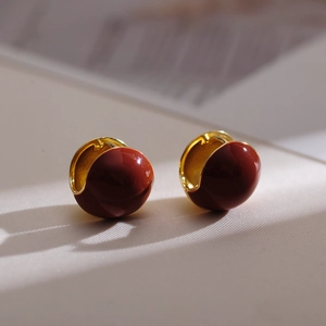 Detail of vintage gold-plated hoop earrings with glossy deep red enamel finish