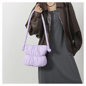 Model wearing a light purple puffy quilted nylon shoulder bag with soft pleated design