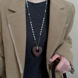 Detail of a brown textured heart pendant with pearls on a long sweater necklace