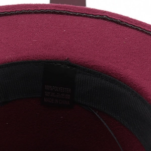 Detailed macro view of 100% polyester fabric care label inside the dark red jazz hat