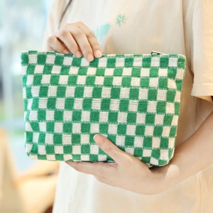 Minimalist green and white checkered knit pouch held by hands for makeup storage