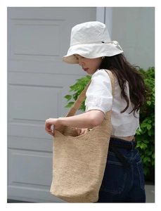 Detail of hand-woven raffia shoulder bag shown with summer hat and vacation outfit