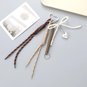 Détail du porte-clés en corde tressée avec nœud en perles et pendentif cœur argenté
