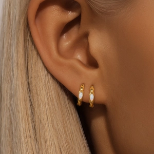 Close-up of gold S925 silver hoop earrings with white opal stone worn by a model