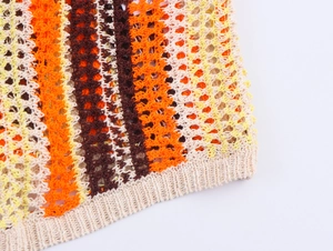 Gros plan du motif en maille ajourée orange et marron sur un polo en tricot crochet
