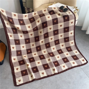 Detail of checkered heart scarf featuring soft brown knit texture and premium roll edge