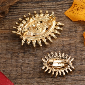 Detailed back view of vintage golden evil eye brooches with secure safety pin fasteners