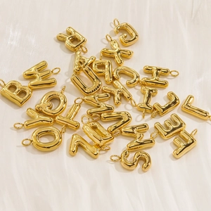 Polished 14K gold stainless steel 26 letter pendants on white glossy fabric background