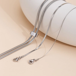 Minimalist silver stainless steel snake chain necklaces wrapped on white display stand