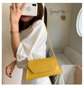 Detail of bright yellow crocodile embossed faux leather shoulder bag with gold hardware