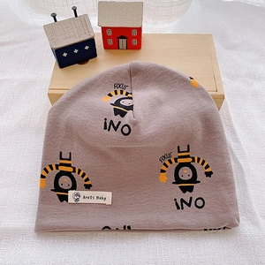 Detailed view of baby cotton beanie with cartoon print and soft knitted texture on wood