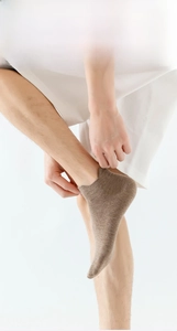 Detail view of light brown cotton ankle socks with elastic cuff for men on feet