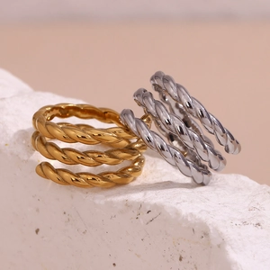 Close-up of triple-layered twisted gold and silver rings on white rock