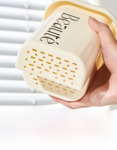 Detail showing the bottom drainage holes of the cream-white cutlery holder with Beauté text
