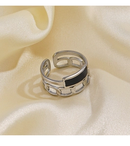 Macro shot of silver chain ring with black enamel inlay on elegant silk fabric