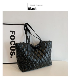 Detail of black glossy quilted tote bag with puffer nylon texture and durable shoulder strap