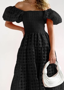 Detail of black off-shoulder puff sleeve dress with textured checkered fabric and tiered skirt
