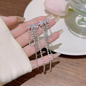 Détail des boucles d'oreilles étoile argentées avec strass blancs et longues chaînes