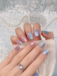 Detail of blue and pink shell press-on nails with gold stars and glitter finish
